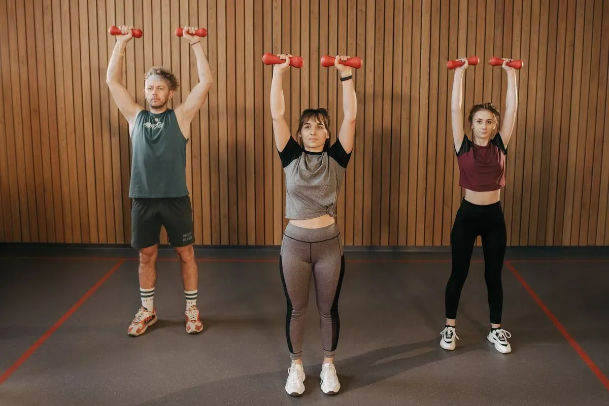 Group class lifting dumbbells overhead
