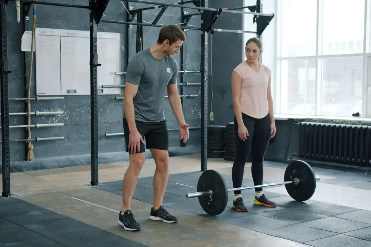 Coach working with a member on a barbell lift